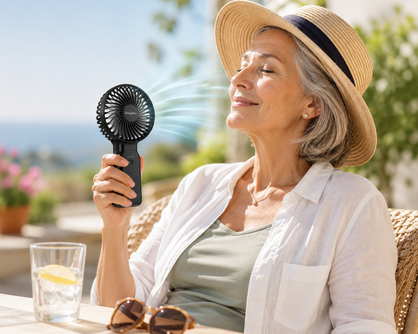 Senior woman relaxing outdoors with a portable handheld cooling fan